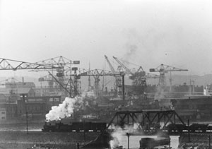 鉄道橋を行く蒸気機関車　昭和29年（1954）３月27日　鉄道橋は現在の汽車道。後方は三菱日本重工業横浜造船所のドックで、現ランドマークタワー一帯